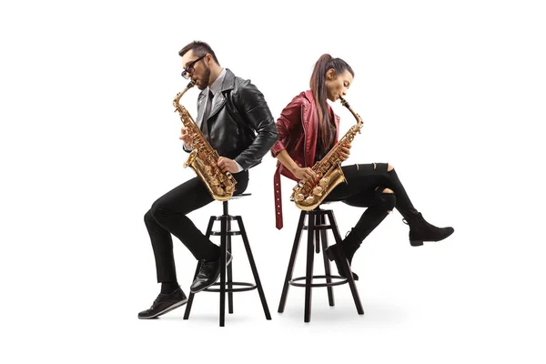 Modern young male and female musicians sitting back to back and playing sax isolated on white background