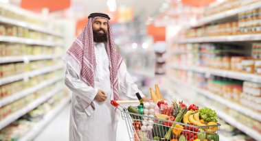Suudi Arabistan 'da süpermarkette bir alışveriş arabası dolusu yiyecek satan bir adam.