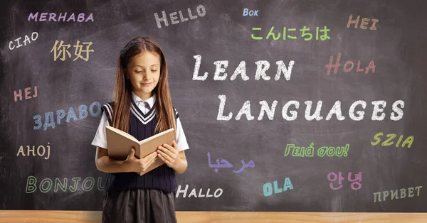 Schoolgirl Reading Book Standing Front Blackboard Message Learn Languages — Stockfoto
