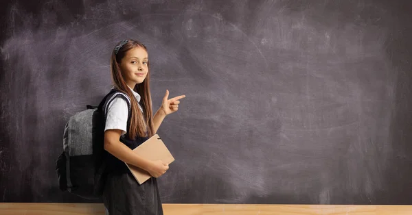 Schoolgirl Backpack Book Pointing Blackboard Looking Camera — Photo