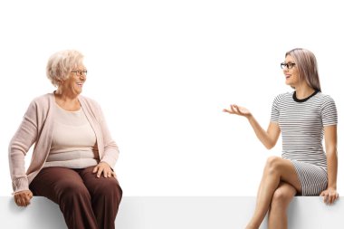 Pensioner and a young woman sitting on a panel and having a conversation isolated on white background