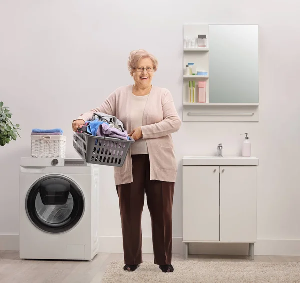 Full Length Portrait Elderly Woman Holding Laundry Basket Clothes Bathroom — Stok fotoğraf