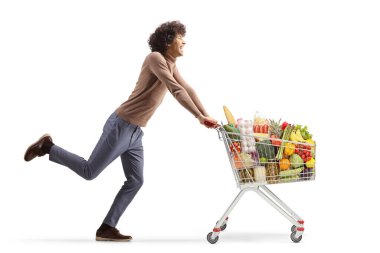 Full length profile shot of a young man running with a shopping cart isolated on  white background