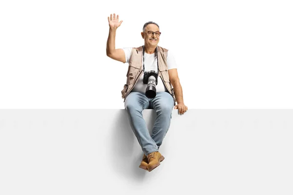 Man Camera Sitting Blank Panel Waving Camera Isolated White Background — Stockfoto