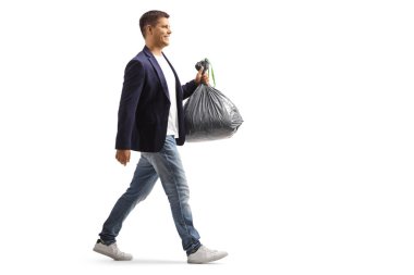 Full length profile shot of a man walking and carrying a plastic waste bag isolated on white background