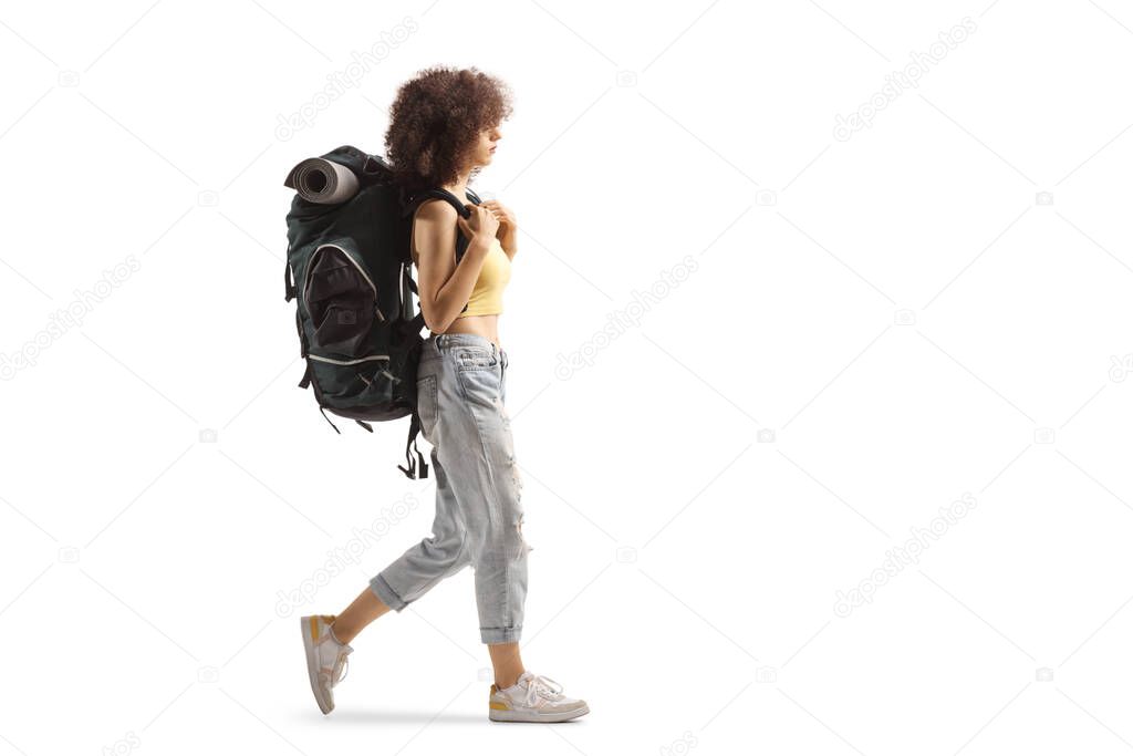 Full length profile of a young female backpacker walking isolated on white background