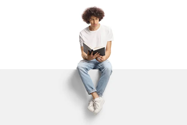 Young Man Curly Hair Sitting Panel Reading Book Isolated White — Zdjęcie stockowe