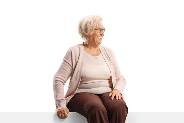 Happy Elderly Woman Sitting Blank Panel Looking Side Isolated White — Foto Stock