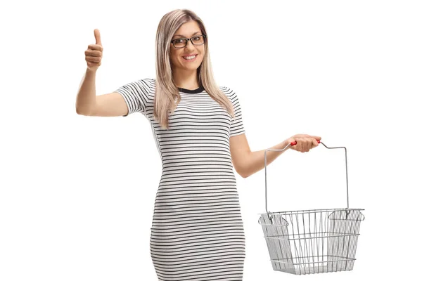 Cheerful Young Woman Posing Empty Shopping Basket Gesturing Thumbs Isolated — Stok fotoğraf