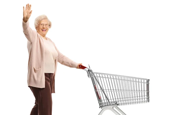 Elderly Woman Waving Pushing Empty Shopping Cart Isolated White Background — Stockfoto