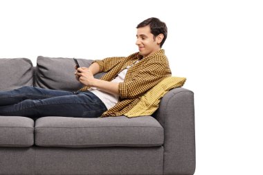 Relaxed man resting on a sofa and looking at a mobile phone isolated on white background