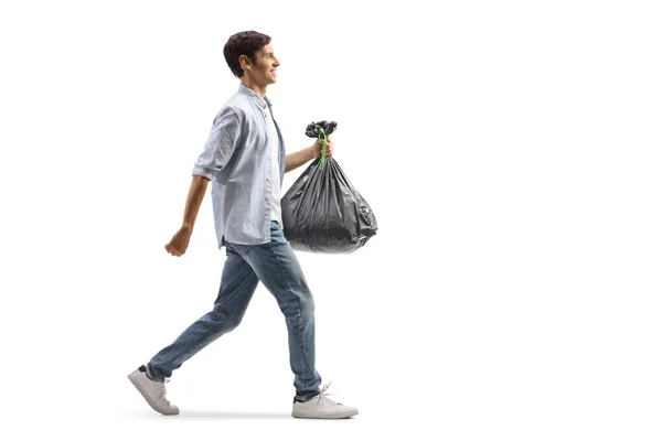 一个漫不经心的男人提着一个塑料垃圾袋走在白色背景下的全景照片 — 图库照片
