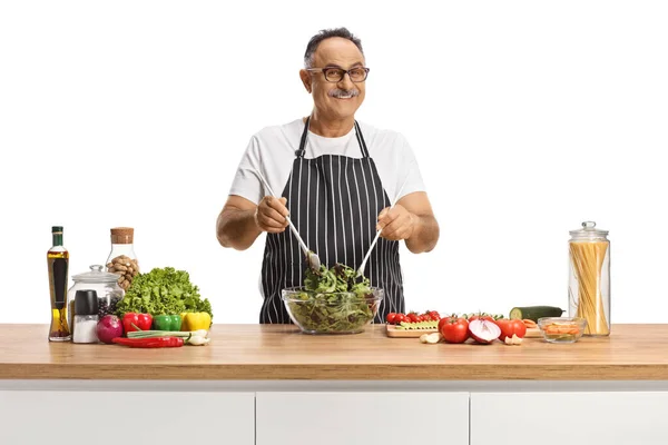 Hombre Maduro Sonriente Mezclando Una Ensalada Recipiente Vidrio Mostrador Cocina — Foto de Stock