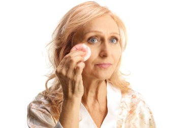 Beyaz arka planda izole edilmiş pamuklu ped ile makyajı kaldıran olgun bir kadın.