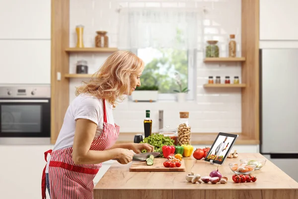 Mature Woman Cutting Vegetables Watching Video Tablet Kitchen — Stock Photo, Image