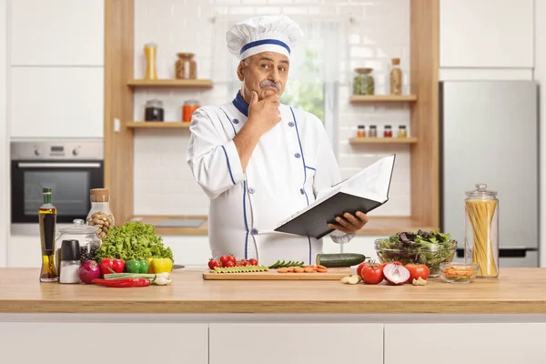Mature Chef Masculin Derrière Comptoir Cuisine Tenant Livre Cuisine Pensant — Photo