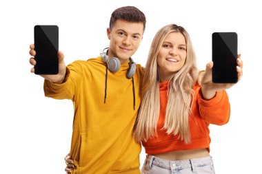 Genç erkek ve kadın akıllı telefon gösteriyor ve beyaz arka planda izole bir şekilde gülümsüyor.