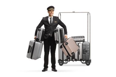 Bellboy bir sürü bavul tutuyor ve beyaz arka planda izole edilmiş bir otel bagaj arabasının önünde duruyor.