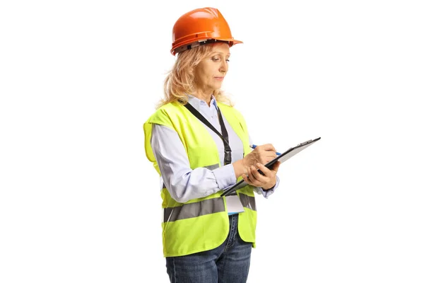 白い背景に隔離された文書を書く安全ベストとヘルメットを持つ女性エンジニア — ストック写真