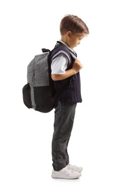 Beyaz arka planda izole edilmiş okul üniformalı üzgün bir çocuğun tam boy profil fotoğrafı.