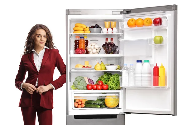 若いですプロの女性は 白い背景に隔離された食品と冷蔵庫にもたれて — ストック写真