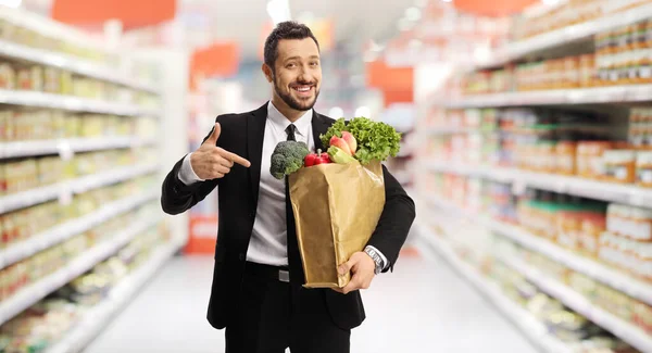 Bussinesman Hält Eine Papiertüte Mit Lebensmitteln Der Hand Und Zeigt — Stockfoto