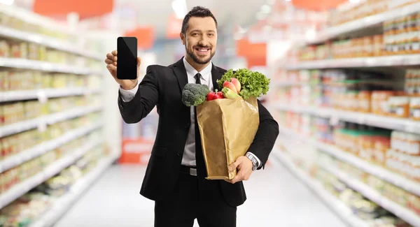 Бизнесмен Держит Сумку Продуктами Показывает Смартфон Супермаркете — стоковое фото