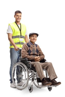 Tekerlekli sandalyenin arkasında yaşlı bir adamla beyaz arka planda duran genç gönüllü.