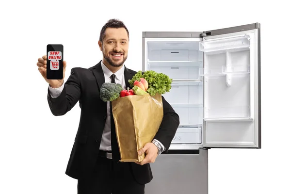 Бизнесмен Пакетом Продуктов Показывает Смартфон Текстовым Магазином Онлайн Перед Холодильником — стоковое фото