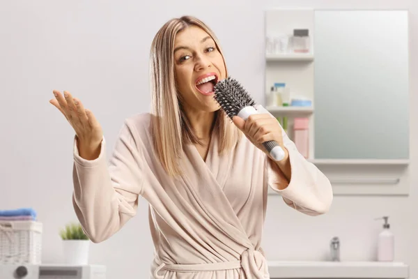 Mujer Joven Feliz Albornoz Cantando Sosteniendo Cepillo Pelo Dentro Baño — Foto de Stock