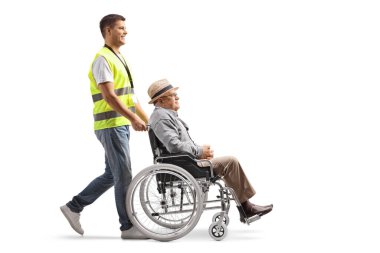 Bir kamu çalışanının, beyaz arka planda izole edilmiş tekerlekli sandalyedeki yaşlı bir beyefendiyi iterken tam boy profil çekimi.