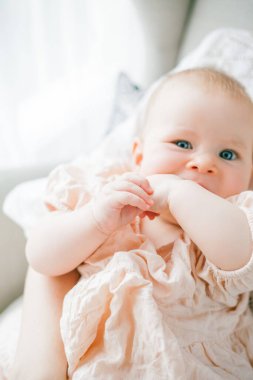 Mutlu genç anne, beş aylıkken kızını kucağında tutuyor. Evdeki bir sandalyede oturuyor..