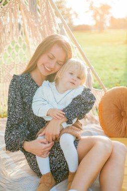 Güzel, genç bir anne ve iki yaşındaki küçük kızı açık havada piknik yapıyorlar. Yaz.