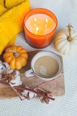 Sonbahar havası. Bir fincan sıcak kapuçino, balkabağı, ahşap bir standa örülmüş sarı ekose. Bir pamuk dalı. kopyalama alanı. Samimi.