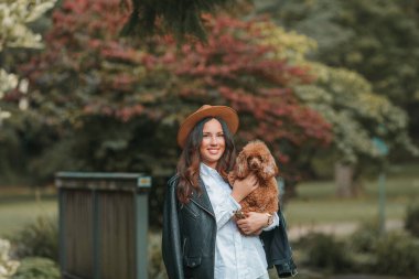 Güzel, genç, siyah saçlı bir kadın parkta yürüyor ve kaniş köpeğine sarılıyor. Sonbahar havası. Düş.