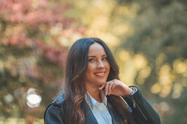 Genç, güzel, koyu renk saçlı kadın sonbahar parkında yürüyor. Düş.