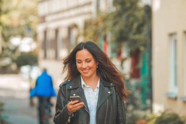 Genç, güzel, koyu renk saçlı kadın sonbahar Avrupa şehrinde yürüyor. Telefonla konuşuyorum. Düş.