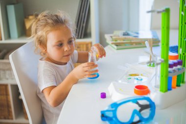 - Bilim. Küçük tatlı kız evde deneyler yapıyor. Renkli sıvılar, laboratuvar çocuk tesisatı. Okul.