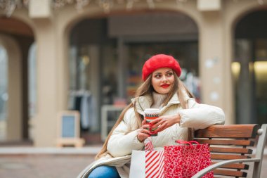 Avrupa 'da kış tatillerinde elinde Noel çantalarıyla gezen güzel bir kadının sokak tarzı portresi. Uzun saçlı, günlük kıyafetlerle şık bir model..