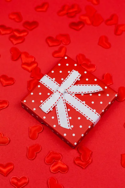 Valentijnsdag plat leggen. Rode geschenkdoos met strikje, valentijn hartjes op een rode achtergrond. — Stockfoto
