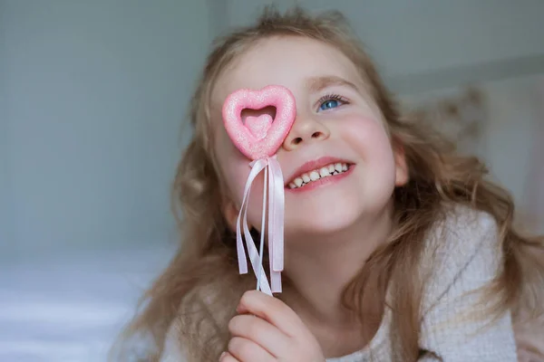 かわいい青い目の女の子は彼女の手にピンクの小さな心を持っています 幸せな子供は贈り物をする バレンタインデー ホーム — ストック写真
