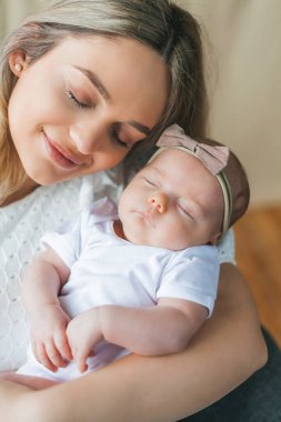 Mavi gözlü genç ve güzel bir anne yeni doğmuş kızını kollarında tutuyor. Annelik. Dikkat et. Bebeğim..