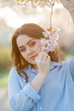 19 yaşında genç ve güzel bir kadın. Pastel tonları içinde, sakura ağaçlarının yanında açık gündelik giysiler giyiyor. Mavi gözlü modelin bahar portresi.