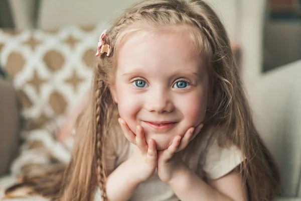 可愛いです青い目の女の子4歳長いです髪は幸せなです座っていますAアームチェアで居心地の良い家. — ストック写真