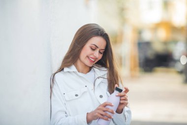 Young beautiful long haired woman drinks water from a refillable bottle outside. Eco friendly. Drink to go. The model is holding an iron bottle in her hands. World.