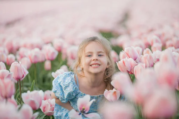 一个漂亮可爱的 可爱的 快乐的 卷曲的 蓝眼睛的小女孩在一片粉色郁金香地里的画像 — 图库照片