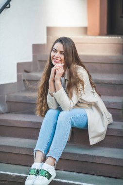 Avrupa 'da güzel, uzun saçlı bir kadının portresi. Havalı bir günlük kıyafet mankeni dışarıda dinleniyor. Bahar.