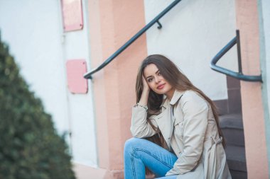 Avrupa 'da güzel, uzun saçlı bir kadının portresi. Havalı bir günlük kıyafet mankeni dışarıda dinleniyor. Bahar.