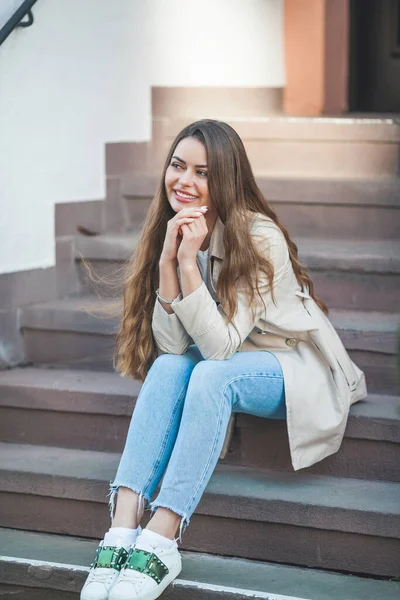 Avrupa 'da güzel, uzun saçlı bir kadının portresi. Havalı bir günlük kıyafet mankeni dışarıda dinleniyor. Bahar.