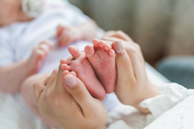 Mavi gözlü genç ve güzel bir anne yeni doğmuş kızını kollarında tutuyor. Annelik. Dikkat et. - Bebeğim. Ev.